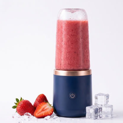 Navy portable blender filled with strawberry smoothie next to fresh strawberries and ice